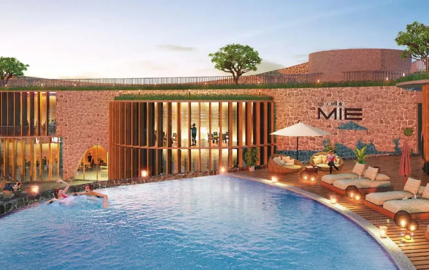 Swimming pool and clubhouse at dusk at Emami Aastha, Joka